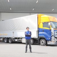 大型トラックの前で男性が腕組