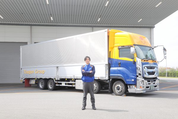 大型トラックの前で男性が腕組